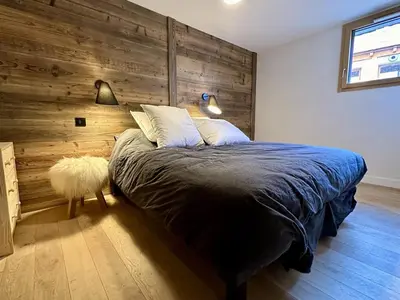 a bedroom with a bed with a wooden wall at Appartement de standing 3P au pied des pistes, terrase privée, parking, à 350m du centre-village - FR-1-572-294 in Arâches-la-Frasse
