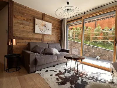 a living room with a couch and a large window at Appartement de standing 3P au pied des pistes, terrase privée, parking, à 350m du centre-village - FR-1-572-294 in Arâches-la-Frasse