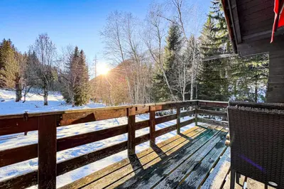 a wooden deck with a fence and snow covered trees at Snowflake cottage with garden in Chamonix-Mont-Blanc
