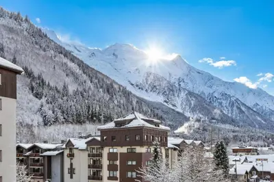 a building with a mountain in the background with snow at Les Marmottes En Chaussettes - Happy Rentals in Chamonix-Mont-Blanc