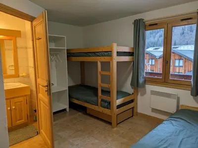 a bedroom with two bunk beds and a window at Appartement Cosy avec Terrasse et Garage in Les Houches