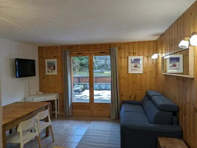 a living room with a blue couch and a table at Appartement Cosy avec Terrasse et Garage in Les Houches