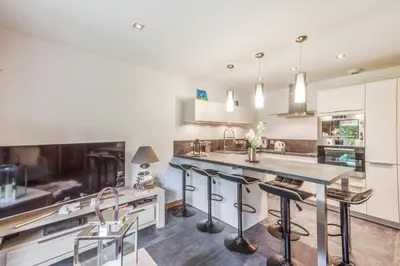 a kitchen with white cabinets and a large island with bar stools at Villa Princesse - Centre-ville - Renove in Chamonix-Mont-Blanc