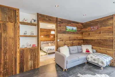 a living room with wooden walls and a couch and a bed at Villa Princesse - Centre-ville - Renove in Chamonix-Mont-Blanc