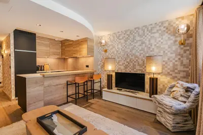 a living room with a television and a couch and a table at Rochebrune - Superbe studio au départ des pistes in Megève