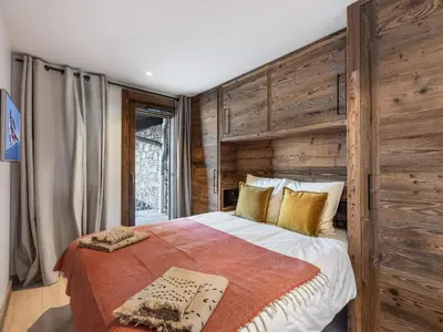 a bedroom with a large bed with a wooden wall at Chalet avec spa partagé, 5 chambres, piscine, parkings à Megève - FR-1-569-187 in Megève