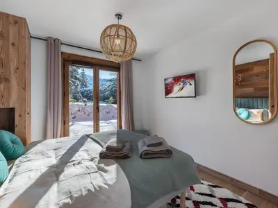 a bedroom with a bed and a mirror and a window at Appartement neuf avec espace bien-être, sauna et hammam - FR-1-569-188 in Megève