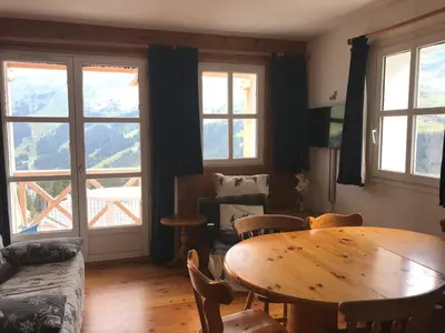 a living room with a table and chairs and windows at Appartement confortable 2 chambres, balcon sud, 6 pers. - FR-1-425-213 in Arâches-la-Frasse