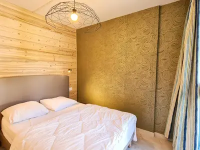 a bedroom with a bed and a wooden wall at Appartement rénové au pied des pistes avec balcon - FR-1-425-215 in Arâches-la-Frasse