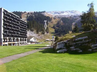 a building on a hill next to a green field at Studio lumineux balcon ski aux pieds - 4 pers. - FR-1-425-223 in Arâches-la-Frasse