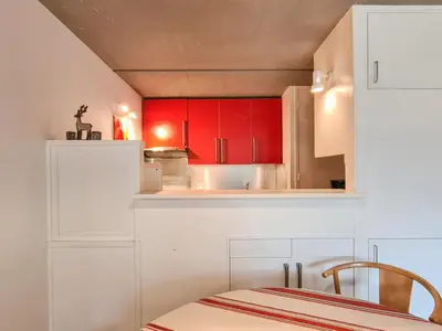 a small kitchen with red cabinets and a table at Appartement spacieux, balcon - 8 pers. - FR-1-425-218 in Arâches-la-Frasse