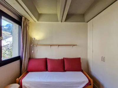 a bed with red pillows in a room with a window at Appartement spacieux, balcon, skis aux pieds - 8 pers. - FR-1-425-216 in Arâches-la-Frasse