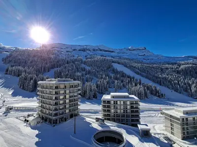 a building in the snow with the sun behind it at Appartement spacieux balcon sud - 6 pers. - FR-1-425-219 in Arâches-la-Frasse