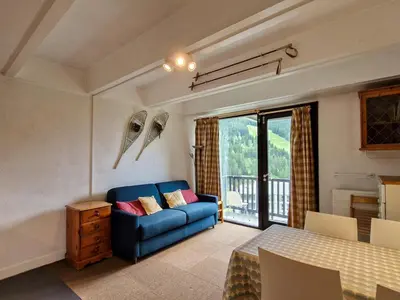 a living room with a blue couch and a table at Studio confortable au pied des pistes - 4 pers. - FR-1-425-224 in Arâches-la-Frasse