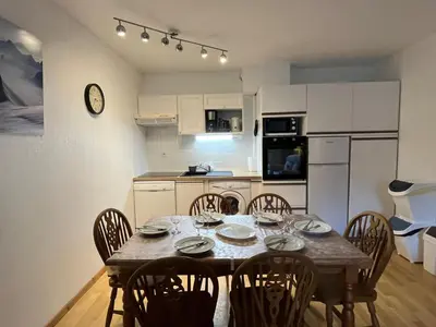 a dining room table with chairs and a kitchen at 3 pièces avec terrasse, animaux admis, parking – Samoëns - FR-1-629-137 in Samoëns