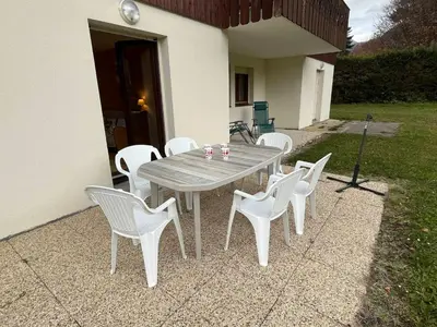 a wooden table and white chairs on a patio at 3 pièces avec terrasse, animaux admis, parking – Samoëns - FR-1-629-137 in Samoëns
