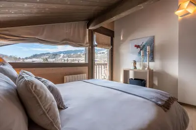 a bedroom with a white bed with a wooden wall at Chalet Satine - Luxe au pied des pistes in Demi-Quartier