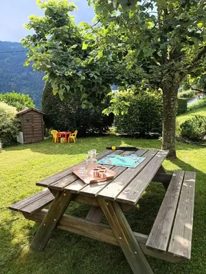 a wooden picnic table in the grass near a tree at Résidence La Planchette - L'Alpin - 4 pièces dans un chalet individuel MAE-7861 in Saint-Gervais-les-Bains
