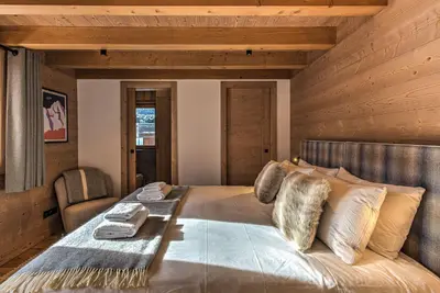 a bedroom with a large bed with a wooden ceiling at Chalet Belle des Neiges - Alpes Travel - Sleeps 9 in Les Houches