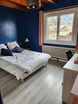 a bedroom with a bed with blue walls and a window at Les Balcons du Mont-Blanc : Appartement centre village in Cordon