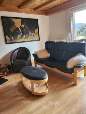 a living room with a black couch and a chair at Les Balcons du Mont-Blanc : Appartement centre village in Cordon