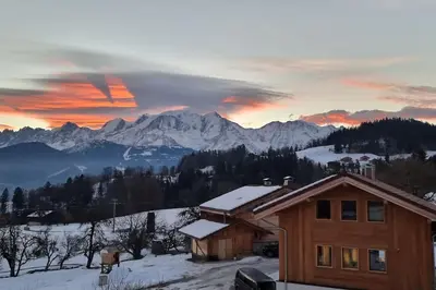a house in the snow with mountains in the background at Les Balcons du Mont-Blanc : Appartement centre village in Cordon