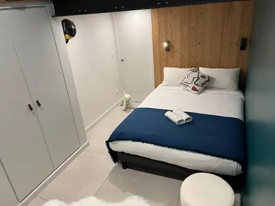 a small bedroom with a bed with a blue blanket at Flaine Forum G1 Cassiopée Mezzanine & Terrasse in Flaine