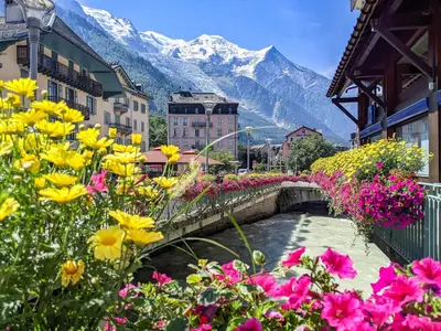 a bridge over a river in a town with flowers at Luxury Studio - Mountain View & 100m to Slopes - Near Chamonix in Les Houches