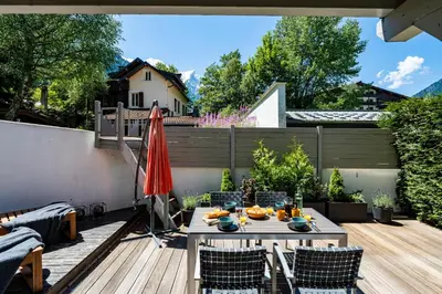 a patio with a table and chairs and an umbrella at Aiguille 1 in Chamonix-Mont-Blanc