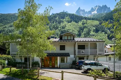 a house with a car parked in front of it with mountains at Aiguille 1 in Chamonix-Mont-Blanc