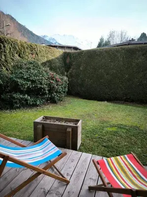 two chairs sitting on a wooden table in a yard at Appartement à 50m des remontées in Saint-Gervais-les-Bains