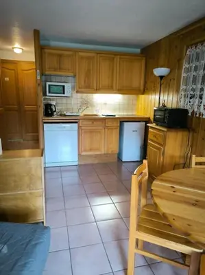 a kitchen with wooden cabinets and a table and a table and chairs at Appartement à 50m des remontées in Saint-Gervais-les-Bains
