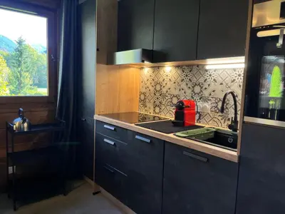 a kitchen with black cabinets and a sink and a window at Appartement rénové avec piscine à Samoëns - FR-1-624-151 in Samoëns