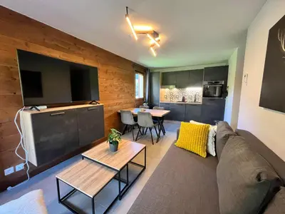 a living room with a couch and a big screen tv at Appartement rénové avec piscine à Samoëns - FR-1-624-151 in Samoëns