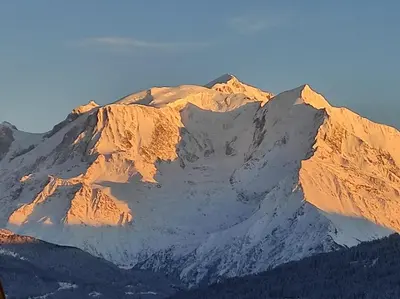 a snow covered mountain with the sun shining on it at Maison Sallanches 12 couchages in Sallanches
