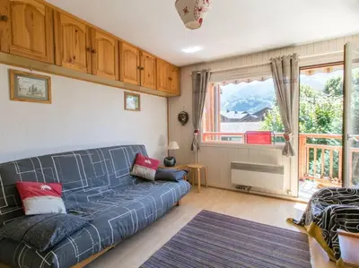 a living room with a blue couch and a window at Appartement cœur de village in Samoëns