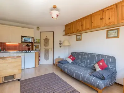 a living room with a couch and a kitchen at Appartement cœur de village in Samoëns