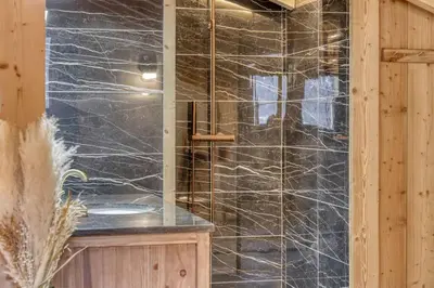 a bathroom with a black marble shower with a sink at chalet Louis situé 25 km Chamonix in Saint-Gervais-les-Bains