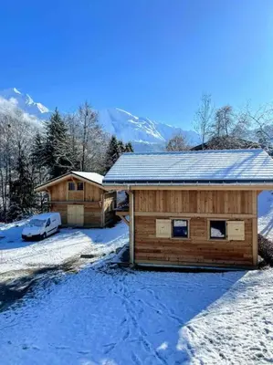 a log cabin with a car parked in the snow at chalet Louis situé 25 km Chamonix in Saint-Gervais-les-Bains