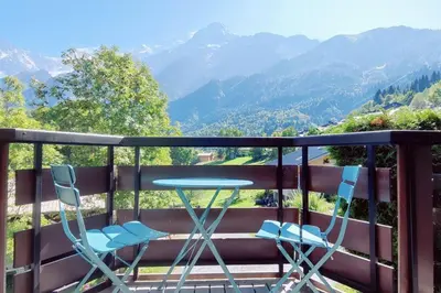 a table and two chairs on a balcony with mountains at Apartement vue Monblanc incroyable ski inout Prarion5 in Les Houches