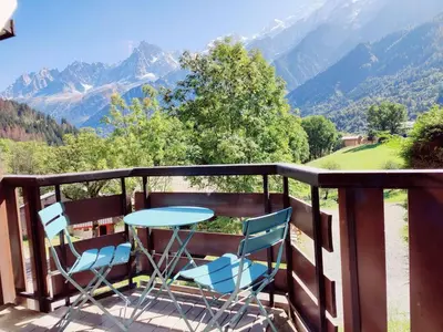 a table and chairs on a balcony with a view of mountains at Apartement vue Monblanc incroyable ski inout Prarion5 in Les Houches