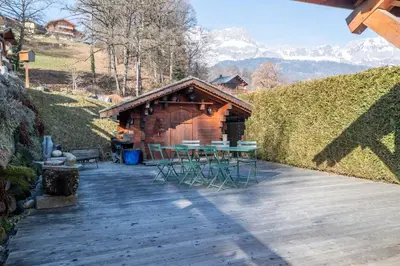 a wooden deck with a table and chairs in front of a building at SmartStay - Chalet face au mont Blanc in Sallanches
