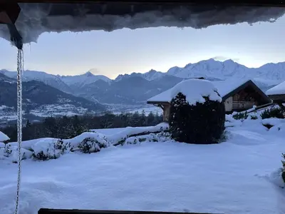 a house covered in snow with mountains in the background at SmartStay - Chalet face au mont Blanc in Sallanches