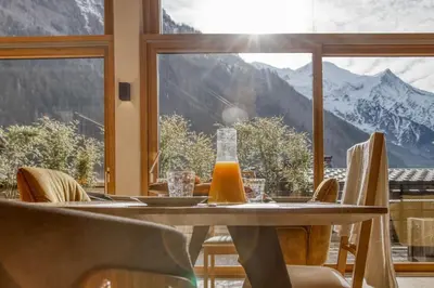 a table with chairs and a view of mountains at Chalet 124 in Chamonix-Mont-Blanc