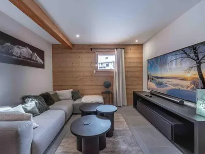 a living room with a couch and a flat screen tv at Chalet moderne à Combloux avec piscine et espace bien-être - FR-1-569-160 in Combloux