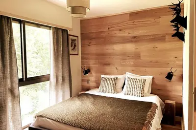 a bedroom with a bed with a wooden wall at Family cocoon Prime Rochebrune location in Megève
