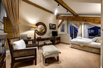 a bedroom with a bed and a chair and a mirror at Chalet Serena - luxury 7 Bedroom Chalet, Pool & Spa in Les Houches