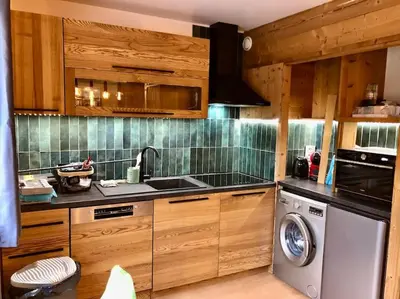 a kitchen with wooden cabinets and a washing machine at Apartement vue montage magnifique 2ch 5mn piste 3 in Les Houches