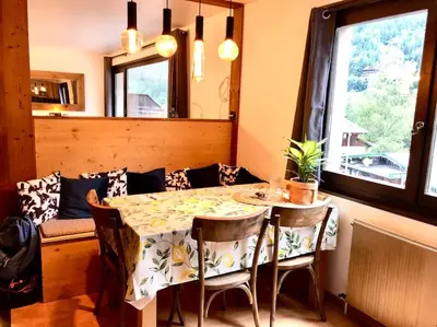 a dining room with a table and chairs and a window at Apartement vue montage magnifique 2ch 5mn piste 3 in Les Houches
