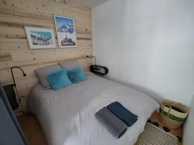 a bedroom with a white bed with blue pillows at Apartement vue montage magnifique 2ch 5mn piste 3 in Les Houches